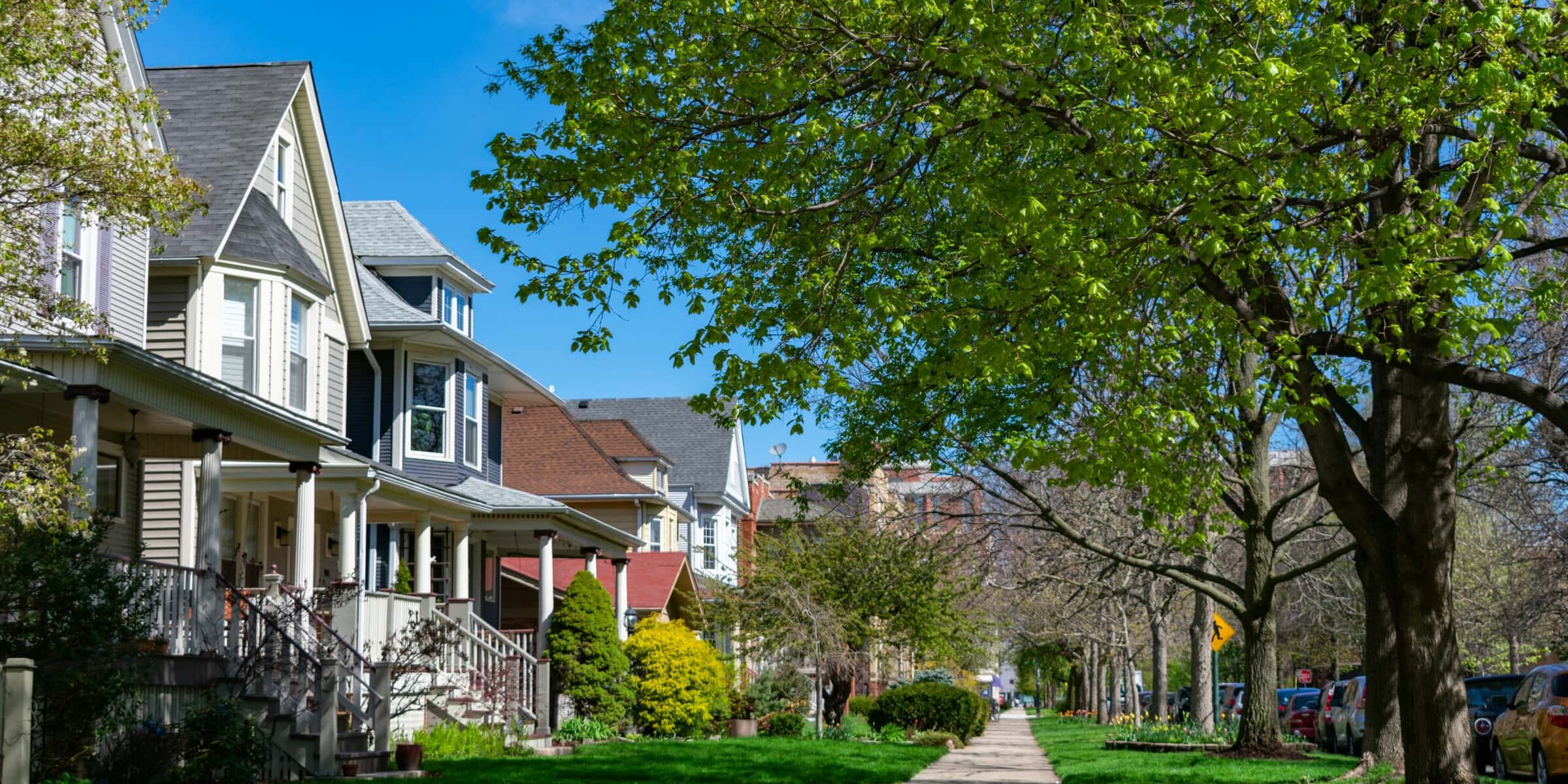 A row of old wooden homes with front lawns and a sidewalk in the North Center neighborhood of Chicago