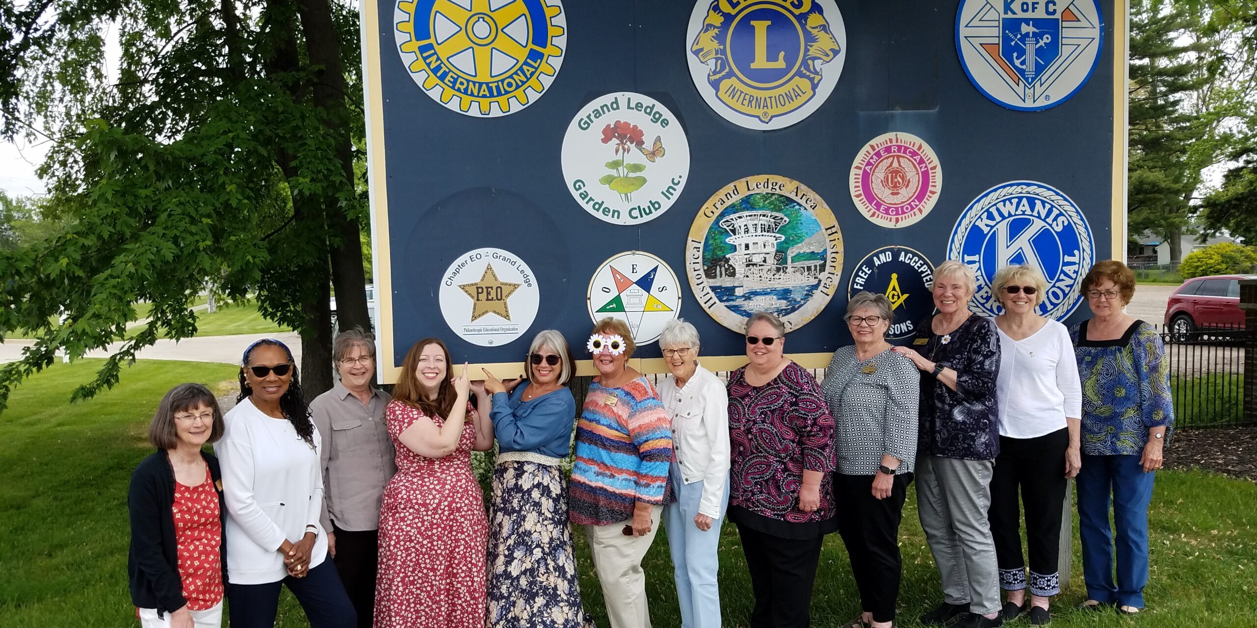 Members of Chapter EO, Grand Ledge Michigan, posing by a P.E.O. sign