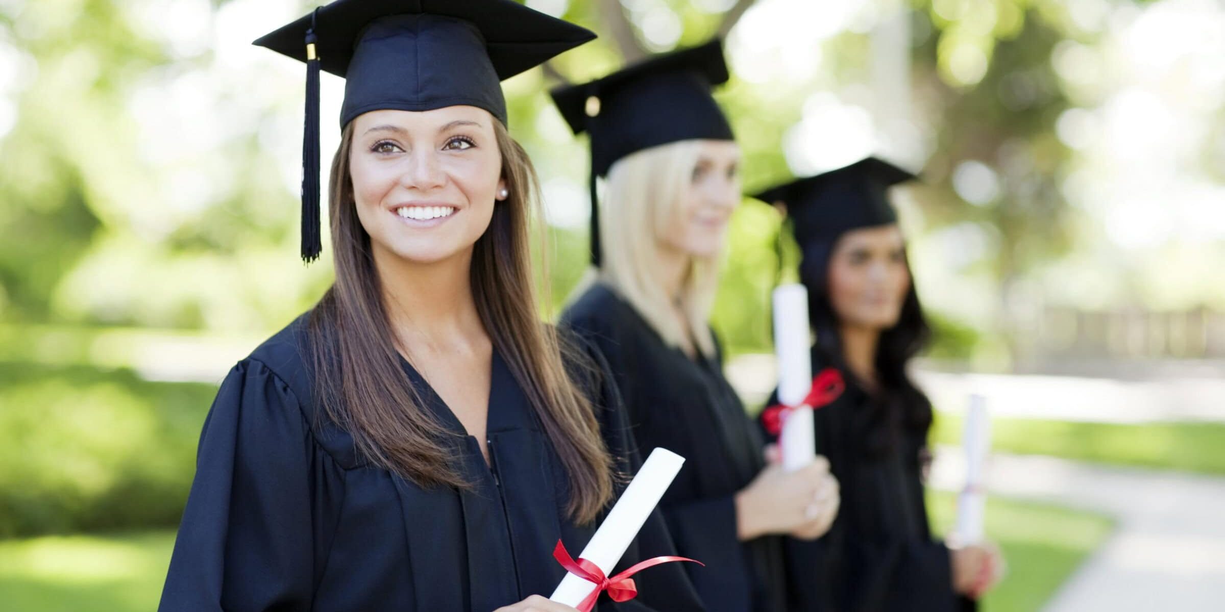 Three young women smile after a college graduation ceremony.