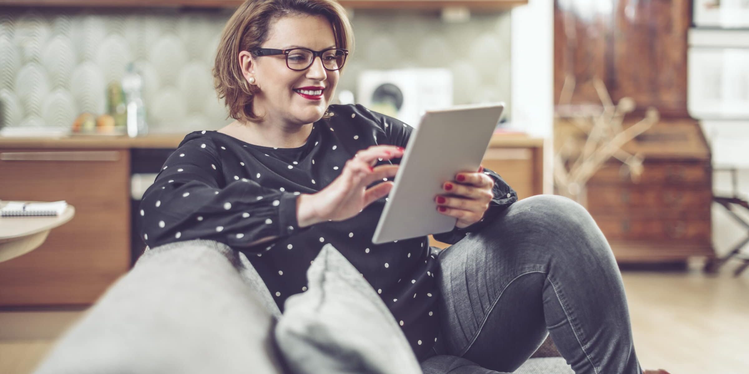 Woman reading her tablet while sitting on the couch
