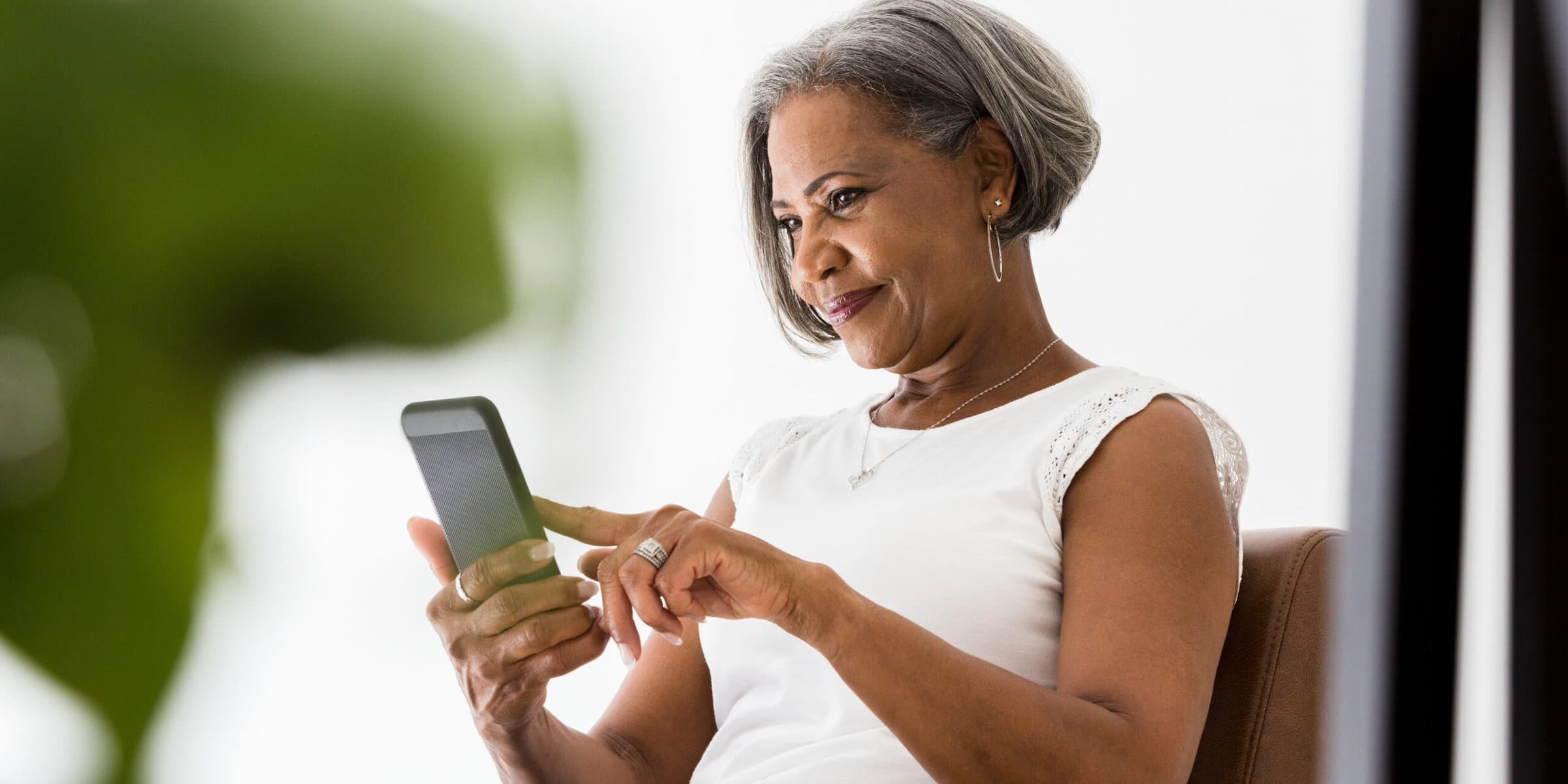 Attractive senior African American woman smiles while video chatting with her grandchildren.