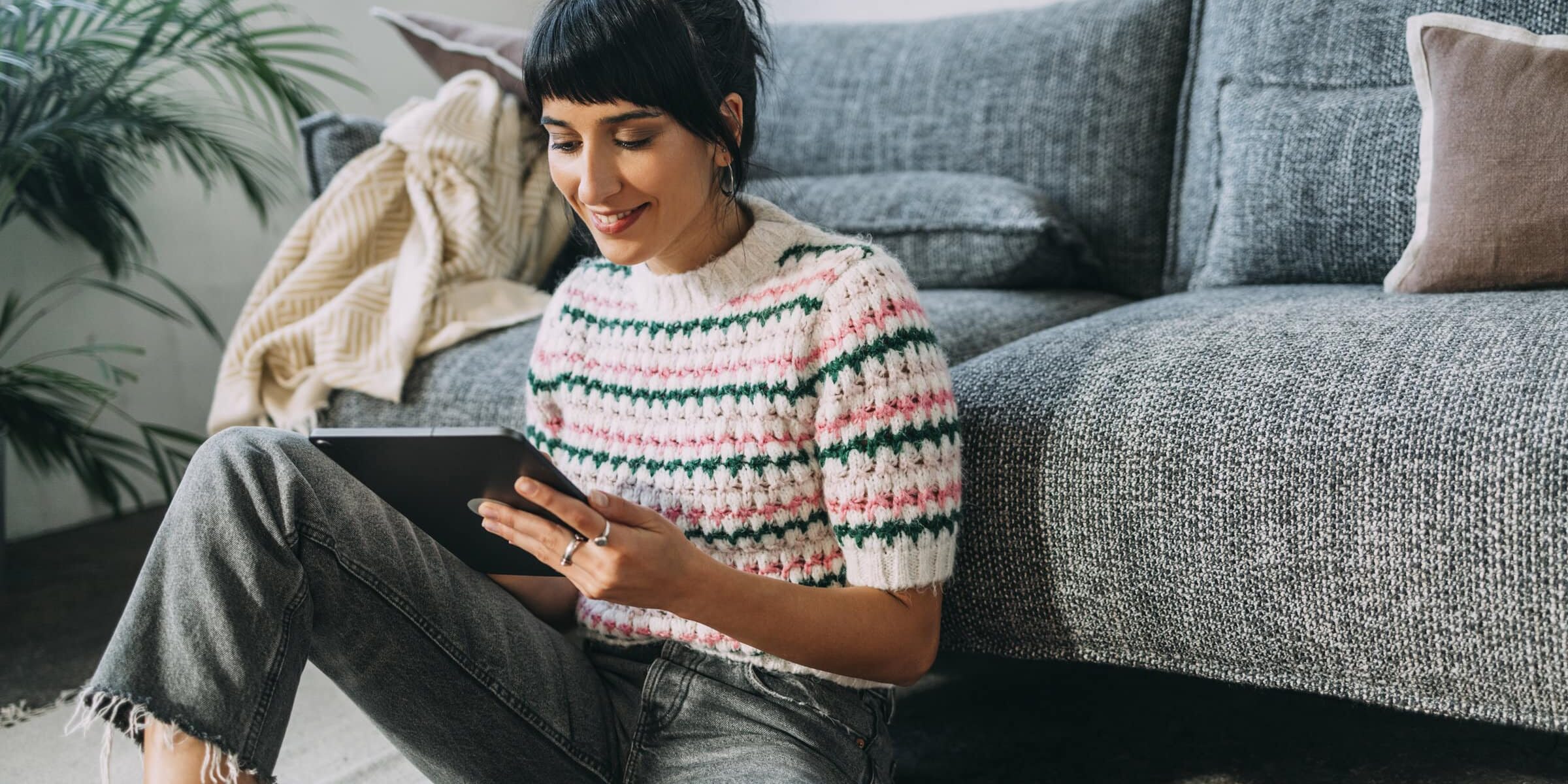 A beautiful woman being entertained by watching something on her tablet.